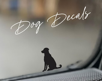 May include: Black silhouette of a dog sitting, with the words "Dog Decals" in cursive script above. The decal is designed for application on a car window or similar surface.