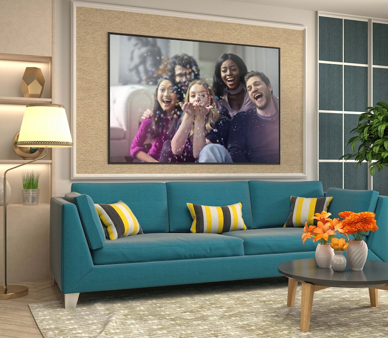 May include: A teal blue sofa with yellow and black striped throw pillows. The sofa is in a living room with a framed photo of a group of friends laughing and a coffee table with a vase of orange flowers.