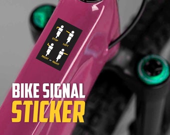 May include: A pink mountain bike with a black and yellow sticker that says "Bike Signal Sticker" and shows four stick figures demonstrating hand signals for stopping, turning left, and turning right.
