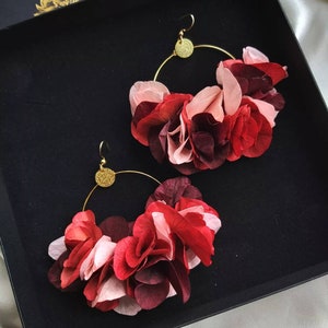 Peut inclure: Une paire de boucles d'oreilles créoles dorées avec un bouquet de fleurs en tissu rose, rouge et bordeaux.