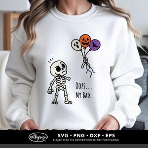 May include: A white long-sleeve sweatshirt featuring a graphic of a skeleton looking at a hand holding three balloons: a white ghost, an orange jack-o'-lantern, and a purple bat. The text "OOPS... MY BAD." is printed in black next to the skeleton.