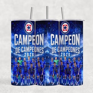 May include: A cylindrical tumbler with a straw featuring a blue stadium background, the Cruz Azul logo, and the text CAMPEON DE CAMPEONES 2026. The design includes a group of soccer players in blue uniforms standing on a field under bright stadium lights.