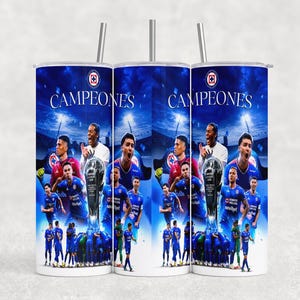 May include: A white 20 oz stainless steel tumbler featuring a blue design with soccer players, a trophy, and the word "CAMPEONES". The design includes the team's logo and a night sky background. The tumbler has a silver straw.
