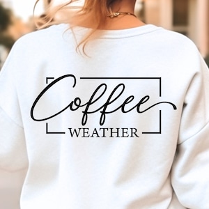 May include: White sweatshirt with black text that reads "Coffee Weather" in a cursive font.