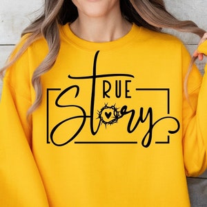 May include: Yellow sweatshirt with a black graphic that says "True Story" with a cross and a heart inside a crown of thorns.