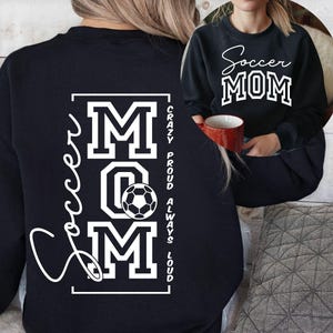 Puede incluir: Sudadera negra con la frase "Soccer MOM" en blanco. La parte trasera de la sudadera muestra "Soccer MOM" con un gráfico de balón de fútbol y las frases "Crazy, Proud, Always, Loud."