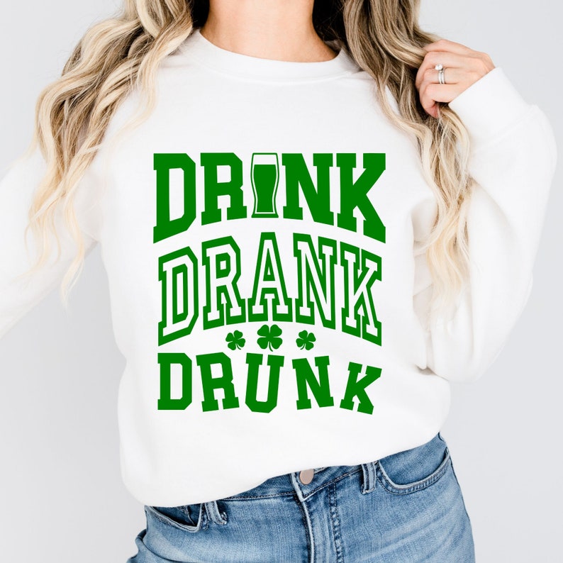 May include: White sweatshirt with green text that reads "DRINK DRANK DRUNK" with a shamrock graphic.