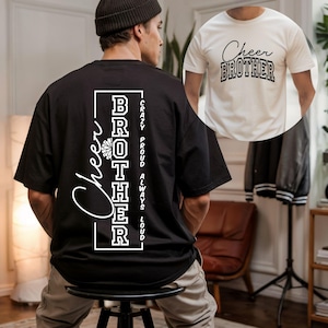 Pode incluir: Camiseta preta com as palavras "Cheer Brother" em escrita branca e letras de bloco. A parte de trás da camiseta apresenta as palavras "Cheer Brother" verticalmente, com "Crazy, Proud, Always, Loud". Uma segunda camiseta branca com o mesmo design também é visível.