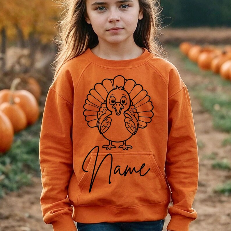 May include: Orange sweatshirt with a black cartoon turkey graphic and the word "Name" printed below.