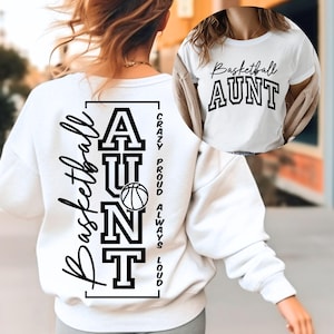 May include: White sweatshirt with the words "Basketball Aunt" and a basketball graphic. The back of the sweatshirt has the words "Basketball Aunt" vertically, with "Crazy, Proud, Always, Loud" printed on the side.