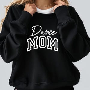 Pode incluir: Camisola de moletom preta com texto branco que diz "Dance MOM" em uma fonte estilizada.