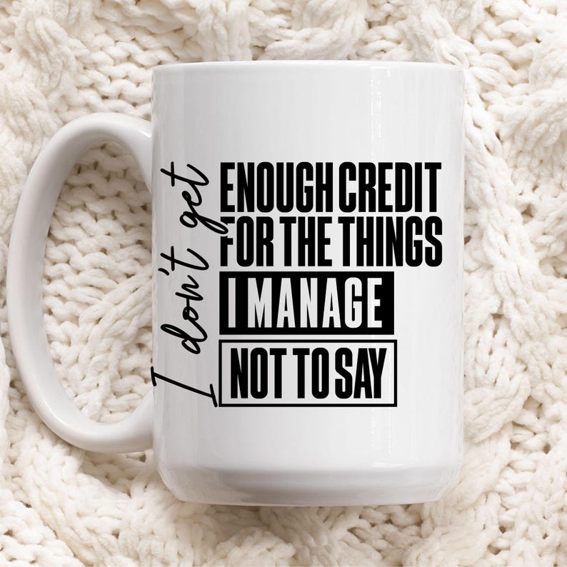 May include: White ceramic mug with the text "I don't get enough credit for the things I manage not to say" in black. The mug has a large handle and is set against a white knitted background.