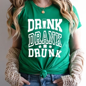 May include: Green t-shirt with white text that reads "DRINK DRANK DRUNK" with a shamrock design.