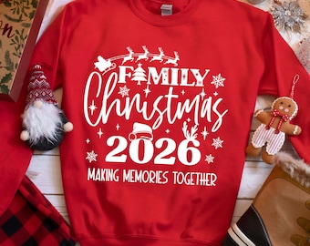 May include: A red sweatshirt with the words "Family Christmas 2026" in white script. The design includes a Santa's sleigh, snowflakes, and the phrase "Making Memories Together". Festive holiday apparel.