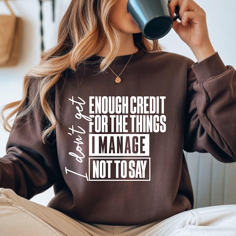 May include: A brown sweatshirt with the text "I don't get enough credit for the things I manage not to say" in white. The sweatshirt is a solid color and has a crew neck.