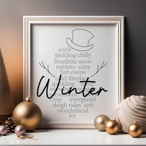 May include: A white framed print with a black and white illustration of a snowman. The text on the print reads "icicle, sledding chilly, frostbite snow, mittens cozy, hot cocoa, cold fireplace, sparkling silent, snow makes snuggle, snowflakes boots, crisp evergreen, sleigh rides soft, wonderland ice". The word "Winter" is written in large, bold, black letters over the snowman.