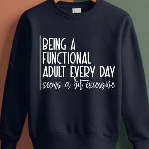 May include: Navy blue sweatshirt with white text that reads "Being a functional adult every day seems a bit excessive."