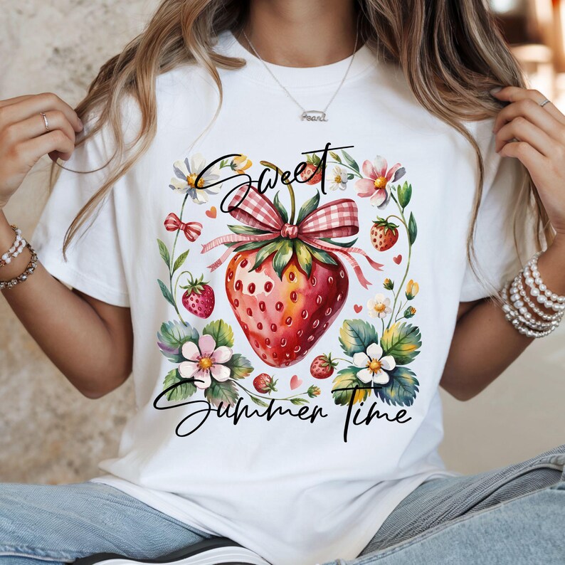 K&ouml;nnte beinhalten: Wei&szlig;es T-Shirt mit einem Aquarell-Erdbeer-Design und den Worten "Sweet Summer Time". Die Erdbeere ist von Blumen und Bl&auml;ttern umgeben, mit einer Vichy-Schleife.