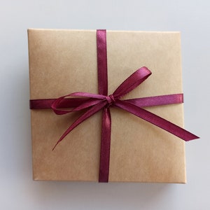 May include: A brown gift box with a burgundy ribbon tied in a bow.