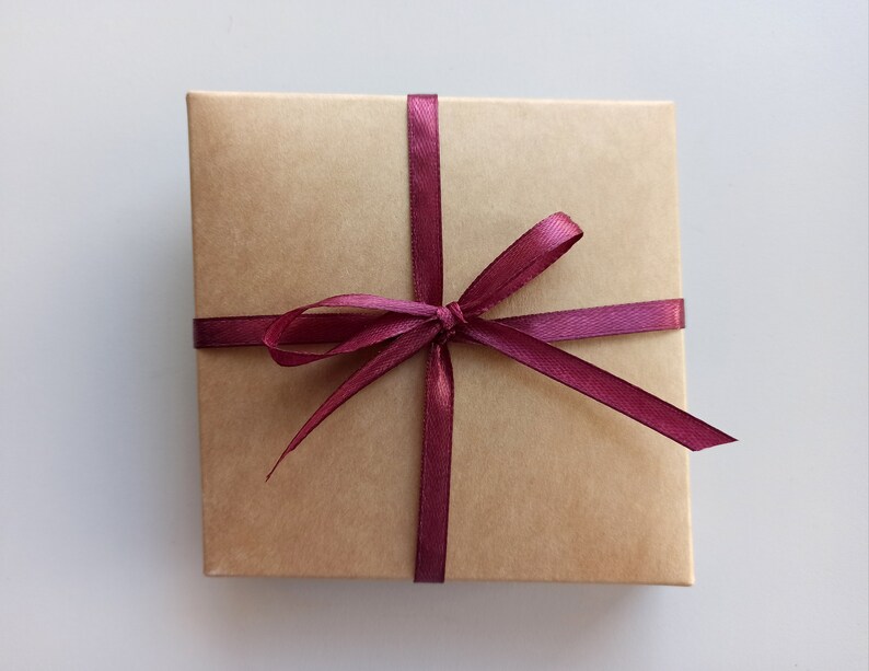 May include: A brown gift box with a burgundy ribbon tied in a bow.