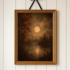 Könnte beinhalten: Ein rechteckiges Gemälde in einem verzierten Goldrahmen, das an einem schwarzen Band hängt. Das Bild zeigt einen Vollmond über einem dunklen, ruhigen See, umgeben von herbstlich gefärbten Bäumen unter einem bewölkten Himmel mit Vögeln.