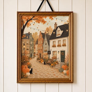 May include: A framed wall art print depicting a European-style street scene in autumn. The illustration features multi-story buildings, string lights, fallen leaves, and numerous orange and white pumpkins lining the cobblestone path.