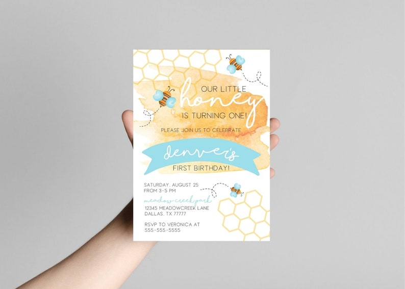 Puede incluir: Una invitaci&oacute;n de baby shower amarilla y azul con un fondo de acuarela y un patr&oacute;n de panal. El texto dice "&iexcl;Nuestro peque&ntilde;o honey est&aacute; cumpliendo un a&ntilde;o!" y "&iexcl;El primer cumplea&ntilde;os de Denver!" La invitaci&oacute;n incluye detalles para la fiesta, incluyendo la fecha, la hora, la ubicaci&oacute;n y la informaci&oacute;n de RSVP.