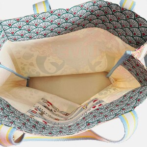 May include: Open view of a tote bag with a patterned exterior and interior. The exterior features a repeating fan design with red hearts. The interior has a floral pattern. The straps are striped with pastel colors.
