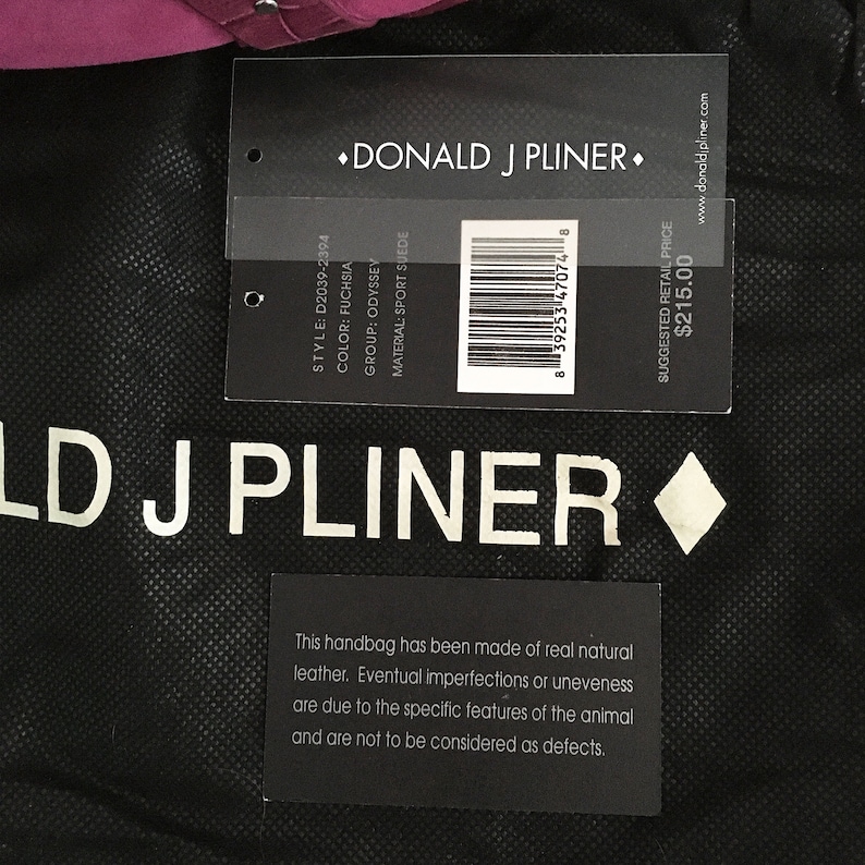 May include: A black handbag with a tag from Donald J Pliner. The tag displays the style, color, group, and material of the bag. The bag is made of real natural leather. The color is fuchsia.