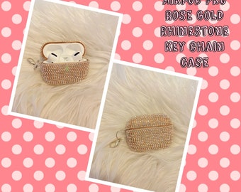 May include: Rose gold Airpod Pro case with a rhinestone design and a key chain. The case is open and the Airpods are visible inside.