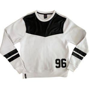 May include: White sweatshirt with black faux leather accents on the shoulders and sleeves. Features two black stripes on each sleeve and the number "96" in black on the front. A casual, sporty style.