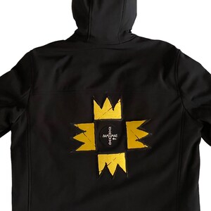 Puede incluir: Chaqueta softshell negra con un parche bordado amarillo y negro en la espalda. El parche presenta una corona y el texto "SAMOVAR".