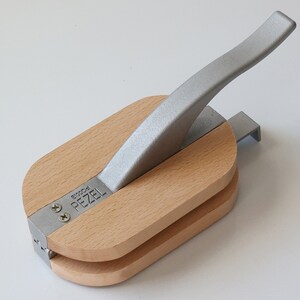 Puede incluir: Un cascanueces de madera con un mango plateado. El cascanueces est&aacute; etiquetado con "Pezel" y "Brooch".