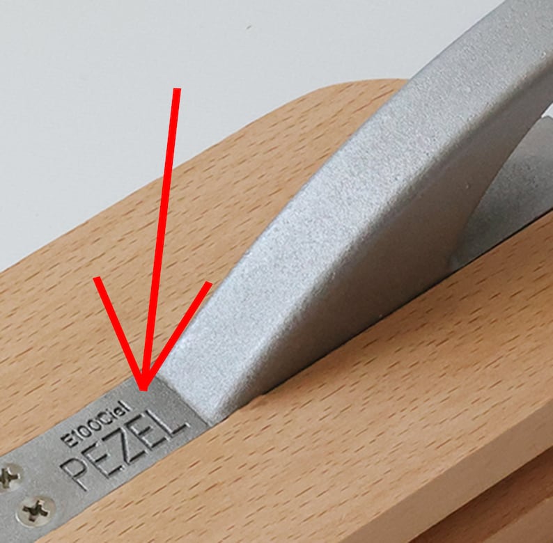 Puede incluir: Primer plano de una herramienta de madera con un mango de metal plateado. La herramienta est&aacute; etiquetada como "Pezel E100Cial".
