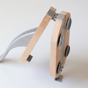 Puede incluir: Un cascanueces de madera y metal con una manija de palanca. El cascanueces tiene una base con cuatro ventosas para mantenerlo estable.