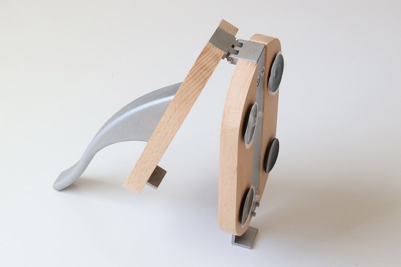 Puede incluir: Un cascanueces de madera y metal con una manija de palanca. El cascanueces tiene una base con cuatro ventosas para mantenerlo estable.