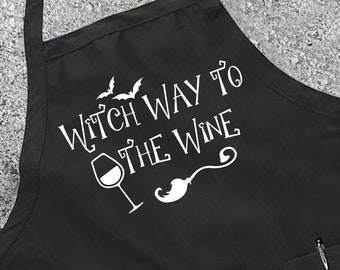 Puede incluir: Delantal de cocina negro con un gráfico blanco que dice "Witch Way to the Wine" con una copa de vino y murciélagos.