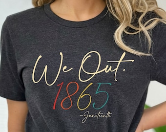 May include: A dark grey t-shirt with the text "We Out. 1865 - Juneteenth" in colorful lettering.