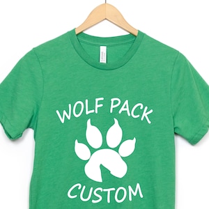 May include: Green t-shirt with a white paw print and the text "Wolf Pack Custom" printed on the front.