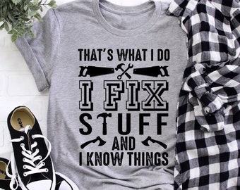 May include: Gray t-shirt with black text that reads "That's what I do I fix stuff and I know things". The text is surrounded by images of tools, including a saw, hammer, and axe.