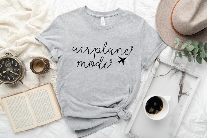 May include: Gray t-shirt with the text "airplane mode" in black cursive writing with a small airplane graphic and hearts.