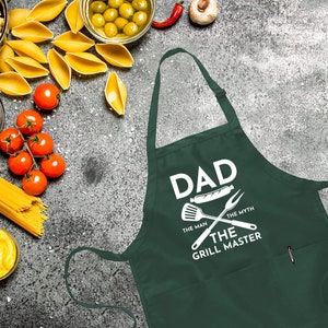 May include: Green apron with a white graphic that says "Dad The Man The Myth The Grill Master" with a spatula, fork, and hot dog graphic.