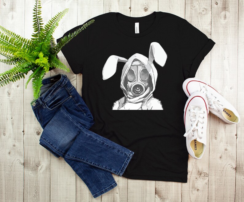 K&ouml;nnte beinhalten: Schwarzes T-Shirt mit einem Aufdruck einer Person mit Gasmaske und Hasenohren.