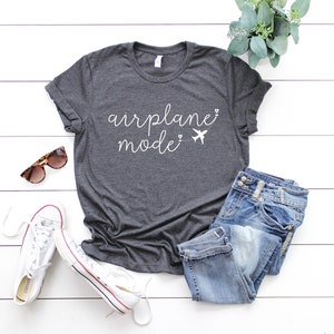 May include: A dark gray t-shirt with the text "airplane mode" in white lettering. The text is accompanied by a small airplane graphic.