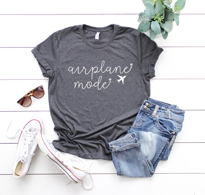May include: A dark gray t-shirt with the text "airplane mode" in white lettering. The text is accompanied by a small airplane graphic.