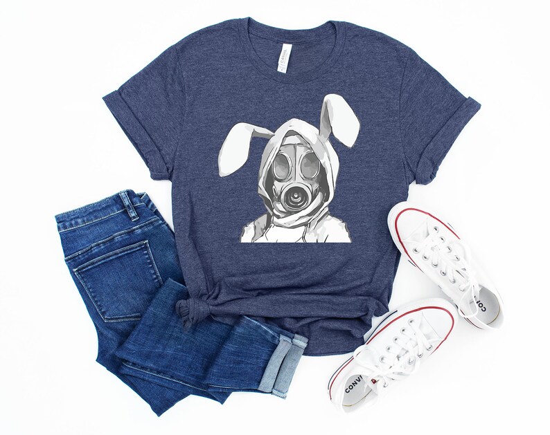 K&ouml;nnte beinhalten: Ein marineblaues T-Shirt mit einem wei&szlig;en Aufdruck eines Kaninchens, das eine Gasmaske tr&auml;gt. Das Kaninchen hat lange Ohren und tr&auml;gt einen Kapuzenpullover.