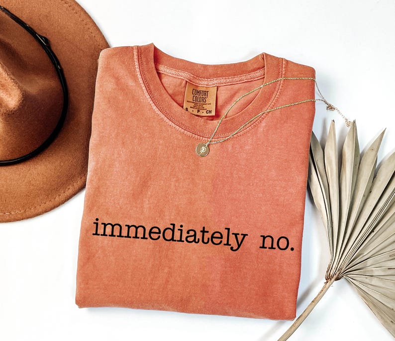 May include: A coral colored t-shirt with the text "immediately no." printed in black.