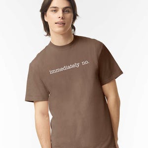 May include: A brown t-shirt with the text "immediately no." printed in white on the front.