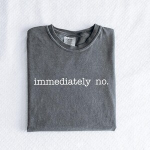 May include: A dark gray t-shirt with the text "immediately no." printed in white.