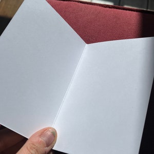 May include: A blank white card folded in half, with a slight crease down the centre.
